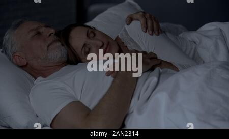 Woman femme poitrine, couple sleeping in bed, man hugging her Banque D'Images