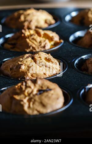 Gros plan sur une rangée de vegan délicieux muffins au chocolat à la vanille dans un moule à muffins noir dans la lumière du soleil - vue oblique verticale, orientation portrait Banque D'Images