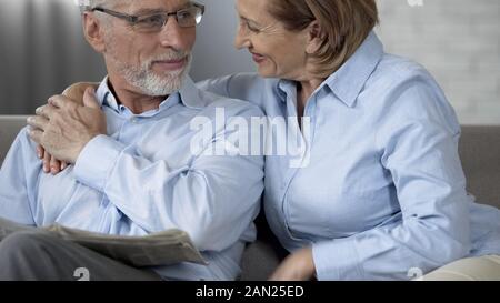 Vieux couple sitting on sofa, regardant et souriant, heureux Banque D'Images