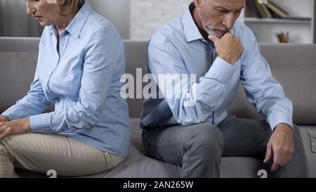 Happy couple sitting on sofa tourné l'un de l'autre, le divorce Banque D'Images