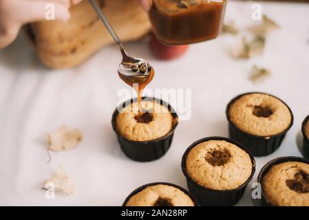 Le Baker crée des cupcakes dans des moules. Biscuits de remplissage avec du caramel liquide. Faire des muffins. Banque D'Images