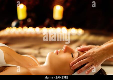 Close up of young woman having massage in spa tête de guérison.Thérapeute faire traitement de manipulation avec des huiles essentielles sur le front. Scène clé faible avec Banque D'Images