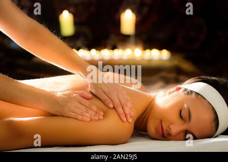 Close up of female therapist massaging spine à spa. Atmosphère à faible clés du flou lumineux bougies en arrière-plan. Banque D'Images