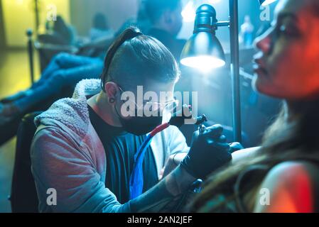 Jeune Femme Obtenir Des Tatouages Dans Le Salon De Beauté Avec Le Travail Tatouiste Banque D'Images