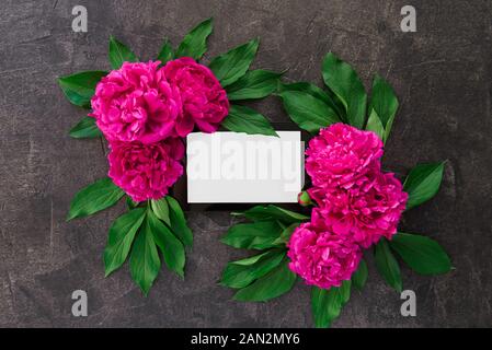 La composition avec tablette avec écran blanc vide en bordure de fleurs violet rose avec des feuilles vertes sur la pierre noire, arrière-plan. Maquette de l'oeuvre Banque D'Images