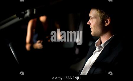 Young man sitting in car et d'attente, femme date romantique, soir Banque D'Images