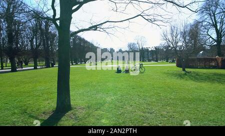 Des gens assis sur l'herbe et se détendre dans le parc de la ville verte à la journée, week-end ensoleillé Banque D'Images