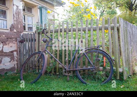 Old rusty bicycle leaning against clôture en bois Banque D'Images