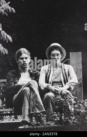 Photographie noir et blanc des années 70 de deux hommes assis sur un banc de parc Banque D'Images