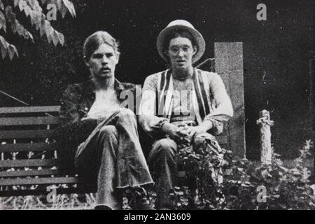 Photographie noir et blanc des années 70 de deux hommes assis sur un banc de parc Banque D'Images