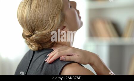 Femme surmenée sentais forte douleur à l'épaule, l'inflammation du nerf, vue arrière Banque D'Images