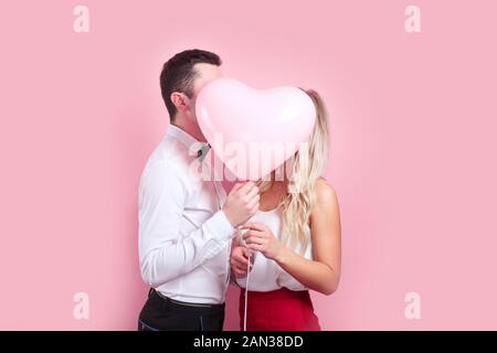 Couple holding heart shaped montgolfière et s'embrasser. Banque D'Images