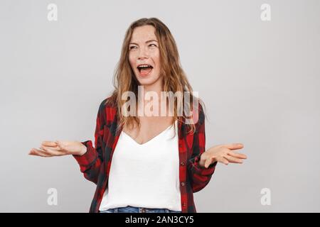 Freestyle. Jeune femme avec des taches de rousseur isolés sur les mains de côté gris confus rire Banque D'Images