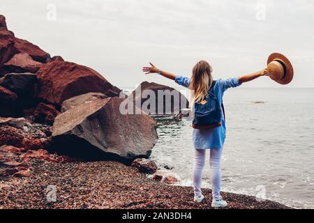 Woman traveler walking bras levés se sentir heureux sur Red Beach sur l'île de Santorin, en Grèce. Tourisme, voyages Banque D'Images