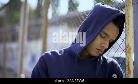 Contrarié boy leaning on fence, enfant migrants séparés de leur famille et placés en détention Banque D'Images