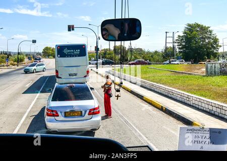 Une femme sans-abri détient son bébé comme elle marche dans le trafic de rue à quémander de la nourriture et de l'argent. Banque D'Images