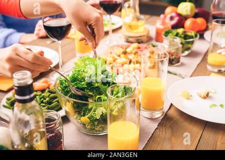 Les gens assis à la maison derrière la table, manger des aliments frais et sains Banque D'Images