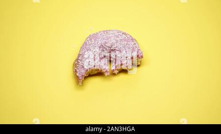 À moitié mangé donut sur fond jaune, la malbouffe et la mauvaise alimentation, macro shot Banque D'Images