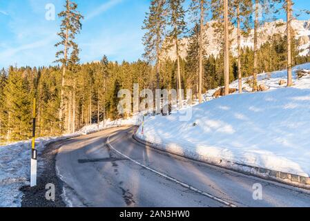 Route de montagne sinueuse débarrassée de la neige dans les Alpes sur une journée d'hiver ensoleillée Banque D'Images