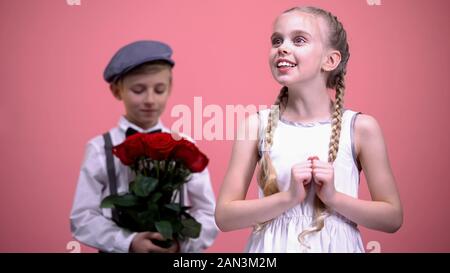 Petit mâle prêt à donner les roses rouges bouquet à peu femme, Saint Valentin Banque D'Images