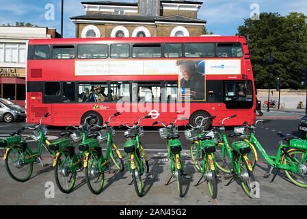 Vélos électriques Lime E sur la chaussée avec bus rouge derrière sur Holloway Road à Highbury Corner, Highbury, London Borough of Islington Banque D'Images