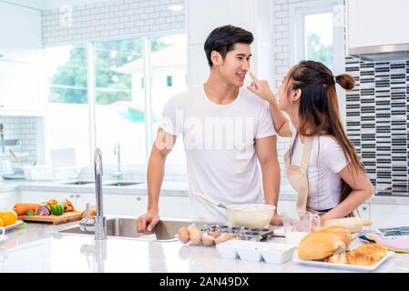 Image couples asiatiques heureux et ustensiles de cuisine cake ensemble dans la salle de cuisine. L'homme et la femme à la tablette à suivre l'étape de recette à la maison. Amour et bonheur c Banque D'Images