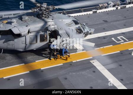 200114-N-FA868-2012 est de la mer de Chine (Janvier 1985). 14, 2020) Les marins affectés au navire d'assaut amphibie USS America (LHA 6) retirer des cales et des chaînes d'un MH-60S Sea Hawk attribué à l'île "Chevaliers" de la mer de l'Escadron d'hélicoptères de combat (HSC) 25 sur le poste de pilotage. L'Amérique, navire amiral de l'Amérique du Nord, groupe expéditionnaire 31e Marine Expeditionary Unit, l'équipe d'exploitation est dans la 7ème Flotte américaine zone des opérations pour améliorer l'interopérabilité avec les alliés et partenaires et servir de force d'intervention pour défendre la paix et la stabilité dans la région Indo-Pacifique. (U.S. Photo de la marine en masse Comm Banque D'Images