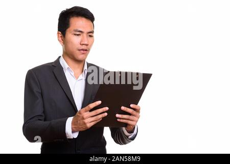 Studio shot of young Asian businessman reading sur presse-papiers Banque D'Images