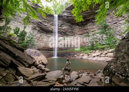 Femme debout et d'admirer les majestueuses chutes d'ozone à Crossville, Tennessee qui plonge à 110 pieds sur un rocher de grès dans une profonde piscine. Banque D'Images