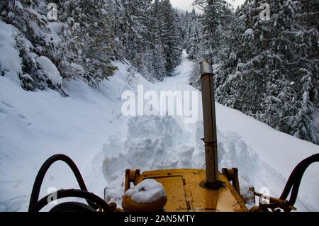 Déneiger sur une route de montagne escarpée, avec un chargeur Cat 931, dans les montagnes de l'armoire, au nord de Noxon, dans le comté de Sanders, Montana Banque D'Images