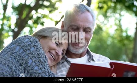 Vieux couple heureux regardant photobook et souriant, agréable, amusant souvenirs de jeunesse Banque D'Images