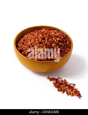 Hot chili flakes dans un bol de couleur moutarde isolé sur fond blanc Banque D'Images