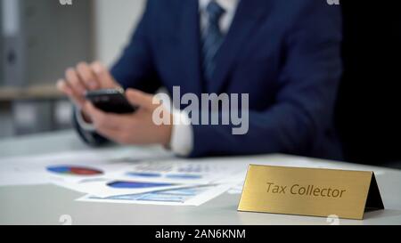 Collecteur d'impôt à l'aide au travail du smartphone, contrôle statistique de la dette dans les diagrammes Banque D'Images