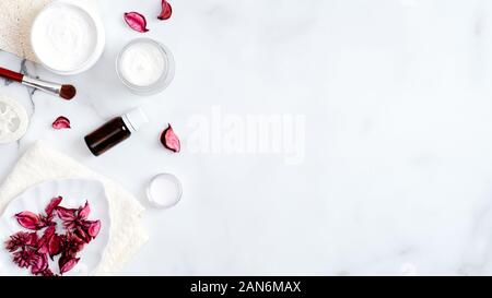 Produits cosmétiques bio naturel SPA sur table de marbre. Vue de dessus pot de crème à la main, bouteille d'huile essentielle, luffa éponge, serviette, brosse, pétales de rose. Un minimum de Banque D'Images