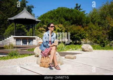 Femme assise sur un parc et à écrire ou à dessiner sur son ordinateur portable Banque D'Images