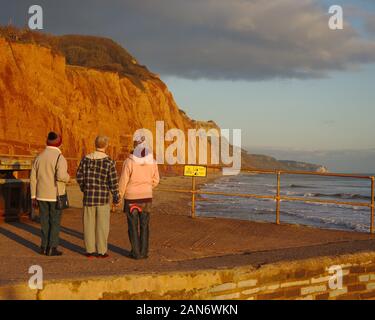 Les gens observant les falaises de grès à Sidmouth au coucher du soleil. La côte jurassique. Devon UK. Banque D'Images