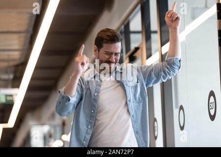 Funny businessman millénaire effectuer gagnant la danse dans l'office de tourisme Banque D'Images