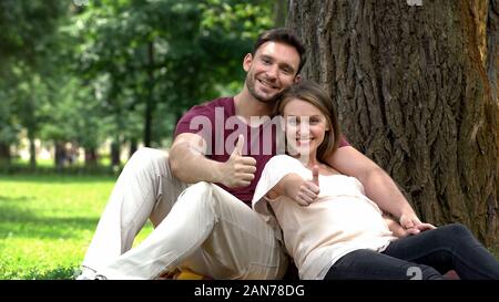 Pregnant couple showing Thumbs up, le soutien social pour les jeunes familles, le bien-être Banque D'Images
