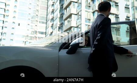 Garde du corps ouvre des portes de voiture pour femme d'affaires, fournit la sécurité pour personne vip Banque D'Images