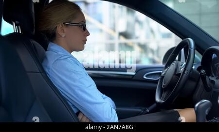 Femme d'hystérique est assise dans sa voiture avec les mains croisées, des problèmes au travail Banque D'Images