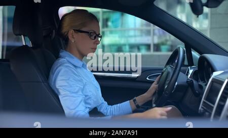 Woman passage des vitesses de la tentative d'exécution voiture, test de conduite de véhicule de luxe Banque D'Images