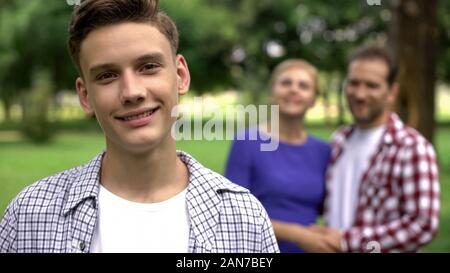 Teenage boy smiling sur fond de bonne humeur, soutien aux parents hugging Banque D'Images