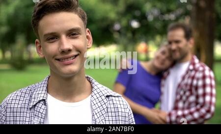 Cute boy smiling sur fond de bonne humeur, soutien aux parents hugging Banque D'Images