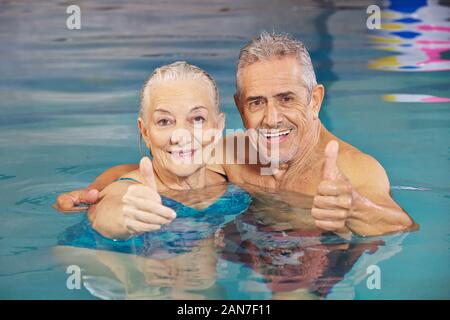 Heureux couple d'aînés détient Thumbs up dans la piscine de l'eau Banque D'Images