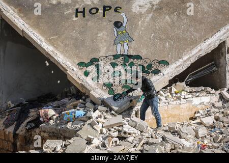 Kafr Nabî, la Syrie. 15 Jan, 2020. Une photo disponible le 16 janvier 2020 montre l'artiste syrien Abu Malik Al-Shami dessiner une fresque graffiti sur le mur d'un bâtiment qui a été détruit dans un bombardement. Al-Shami a commencé à peindre des murales retour en 2014 sur les murs de l'a détruit des bâtiments de sa ville natale assiégée puis de Darayya, situé à au sud-ouest de Damas. Après son déplacement, l'artiste a continué à peindre des murales à Idlib pour attirer l'attention sur la situation humanitaire catastrophique. Credit : Anas Alkharboutli/dpa/Alamy Live News Banque D'Images