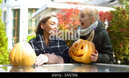 Fille portant pumpkin jack-o-lanterne à mère, la préparation pour l'Halloween Banque D'Images