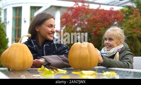 Cheerful girl et maman peinture sur visage effrayant de citrouilles, de passer du temps ensemble, de plaisir Banque D'Images