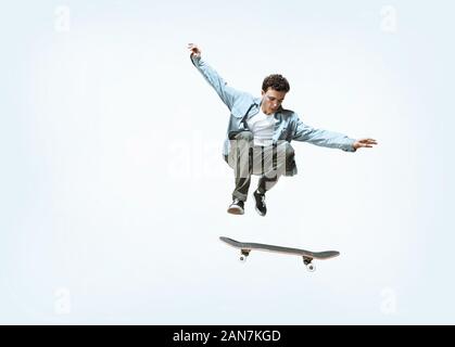 Portrait jeune skateur professionnel équitation isolated on a white background studio. L'homme dans des vêtements décontractés, le saut, la formation pratique en mouvement. Concept de hobby, vie saine, jeunesse, action, mouvement. Banque D'Images