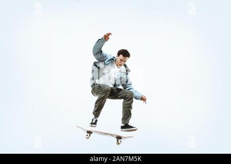 Portrait jeune skateur professionnel équitation isolated on a white background studio. L'homme dans des vêtements décontractés, le saut, la formation pratique en mouvement. Concept de hobby, vie saine, jeunesse, action, mouvement. Banque D'Images