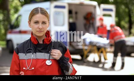 Paramedic posant pour l'appareil photo, l'équipage d'ambulance transport patient on background Banque D'Images